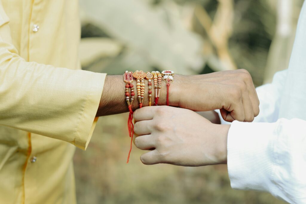 Close-up of hands exchanging colorful Rakhi bracelets during a traditional Indian festival in Kuttanad, Kerala.